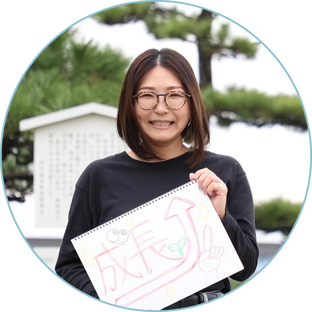 「成長」と書いたスケッチブックを持つスタッフ
